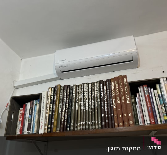 מזגן מותקן על קיר מעל מדף ספרים